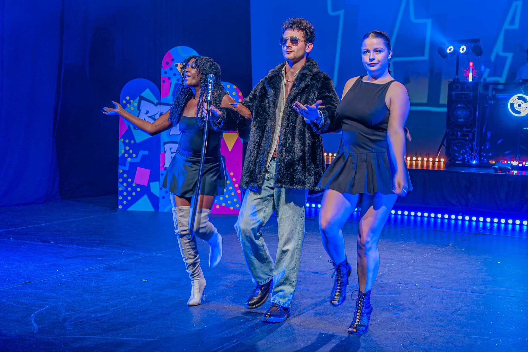 Group of performers moving across the stage during a 90s musical show.
