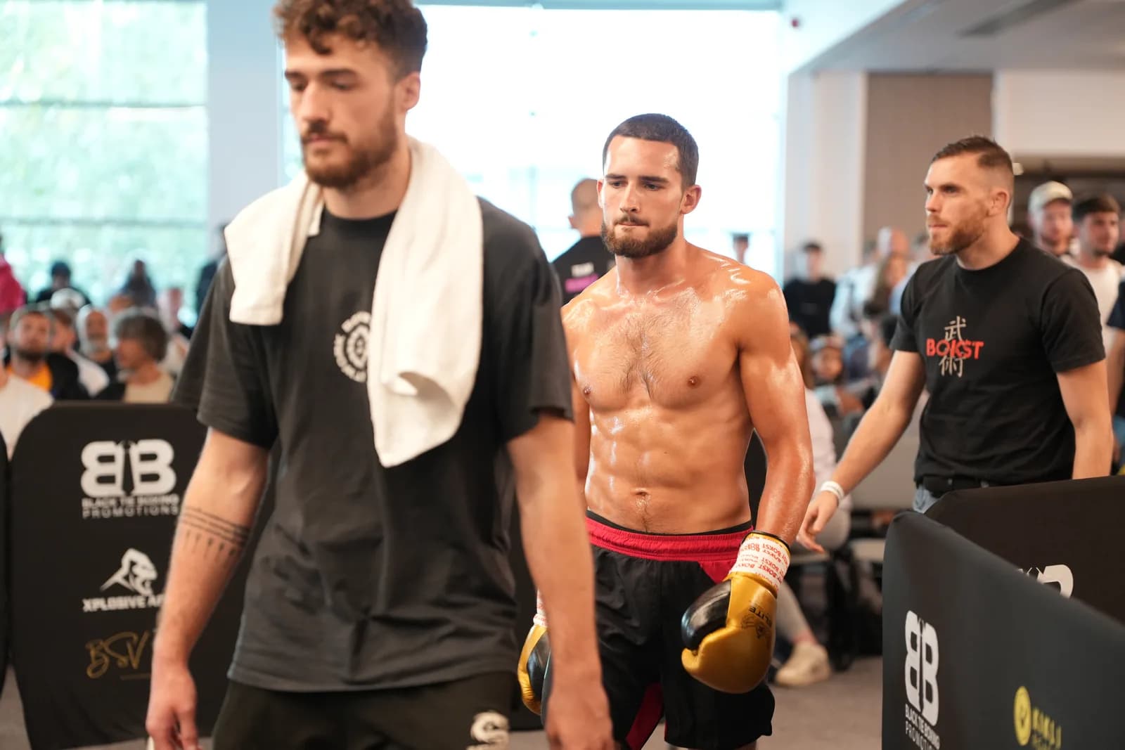 XFC fighter walking out with towel and gloves in a clean documentary frame.