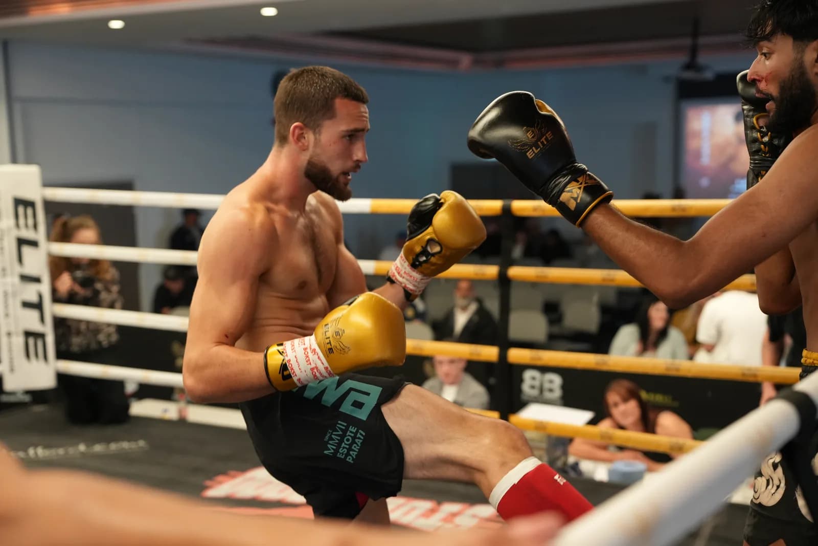 XFC Muay Thai fighter landing a body kick with the ring and crowd behind.