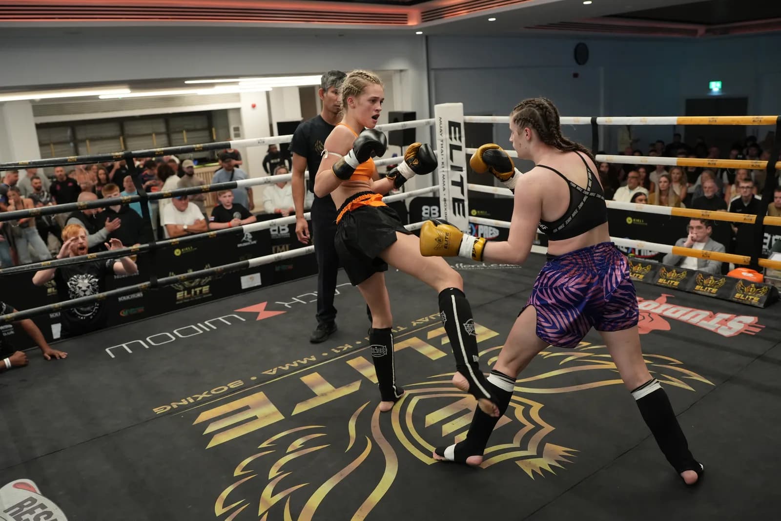 Wide XFC ringside image showing two fighters exchanging kicks in the centre of the ring.