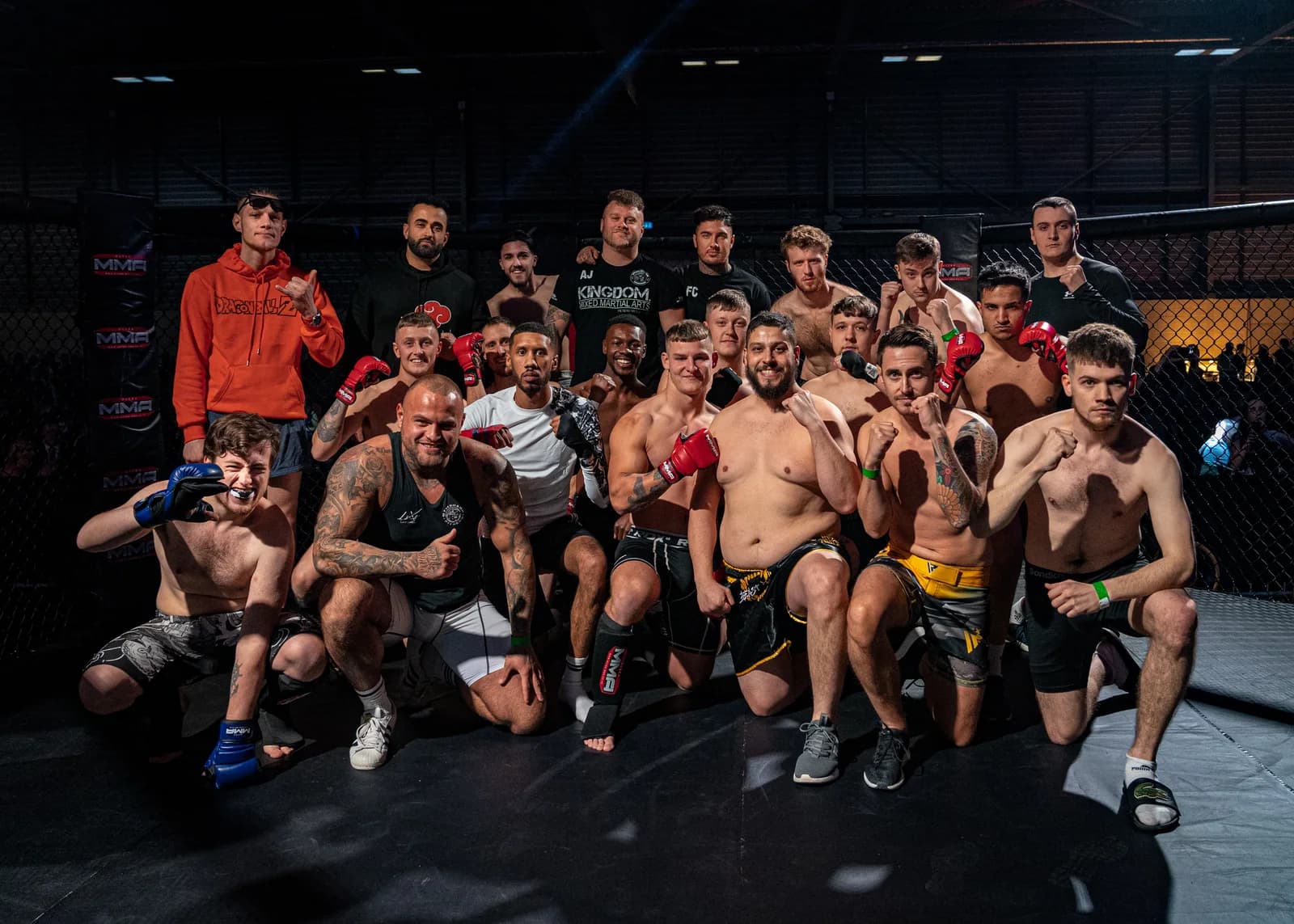 Post-event team group portrait with fighters and coaches gathered at a combat sports venue.