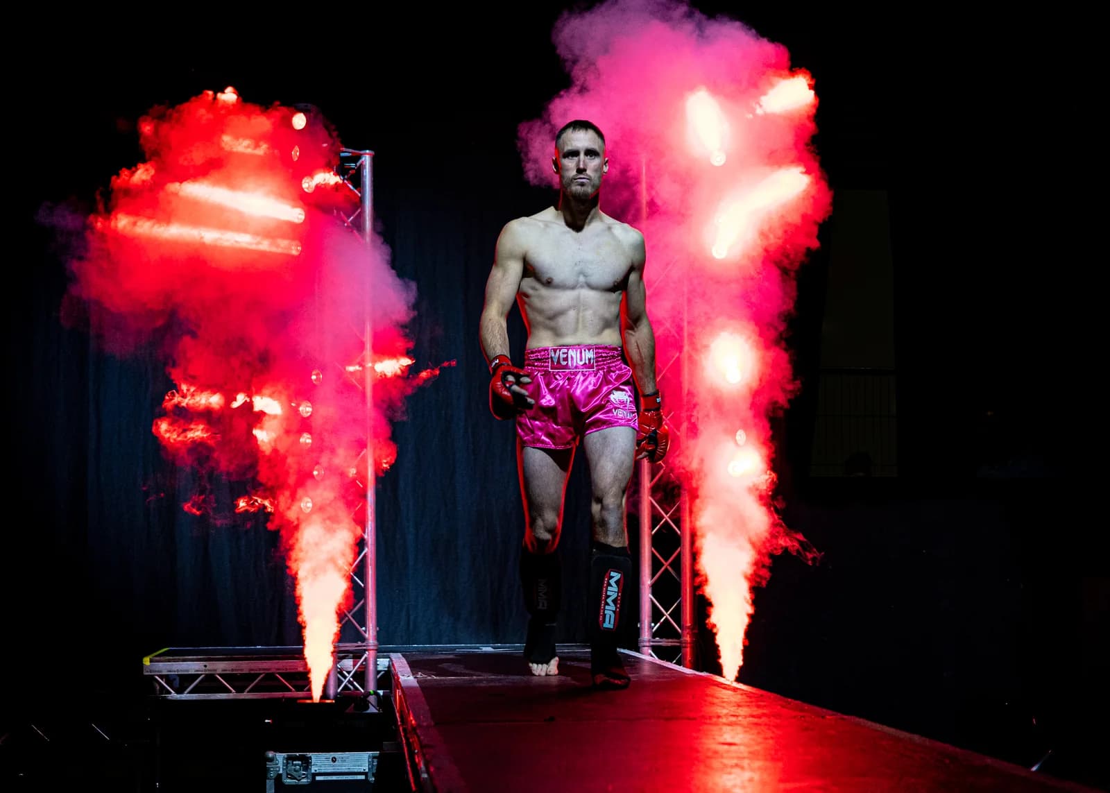 Fighter standing between red pyrotechnics during a dramatic walkout entrance.