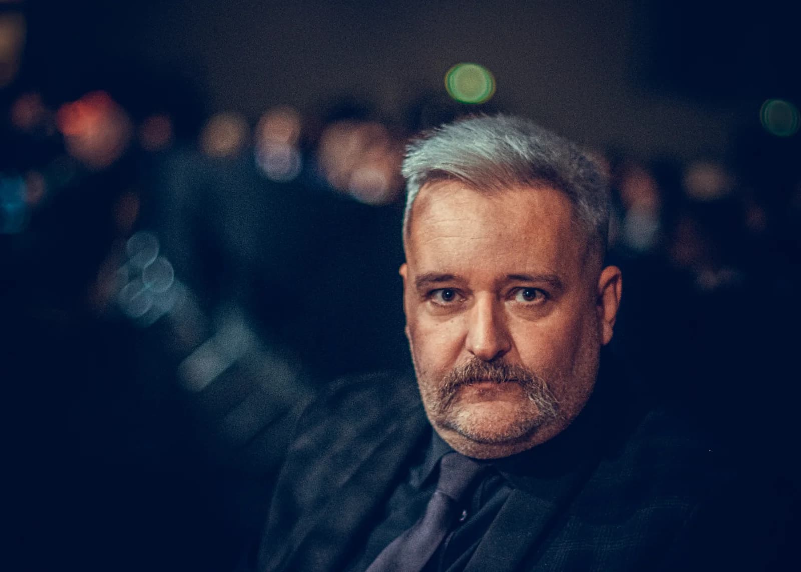 Shallow-depth portrait of an event attendee under low fight-night venue lighting.